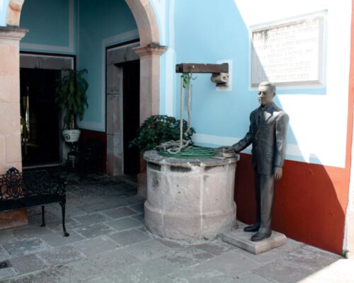 Imagen del patio Museo López Velarde, donde se aprecia al poeta de pie a lado del pozo